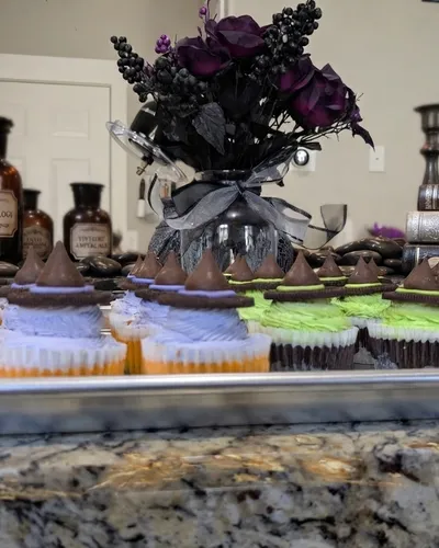 Mini cheesecakes topped with chocolate Hershey's Kiss "witch hats" and orange and lavender frosting, styled with apothecary jars for a Halloween party